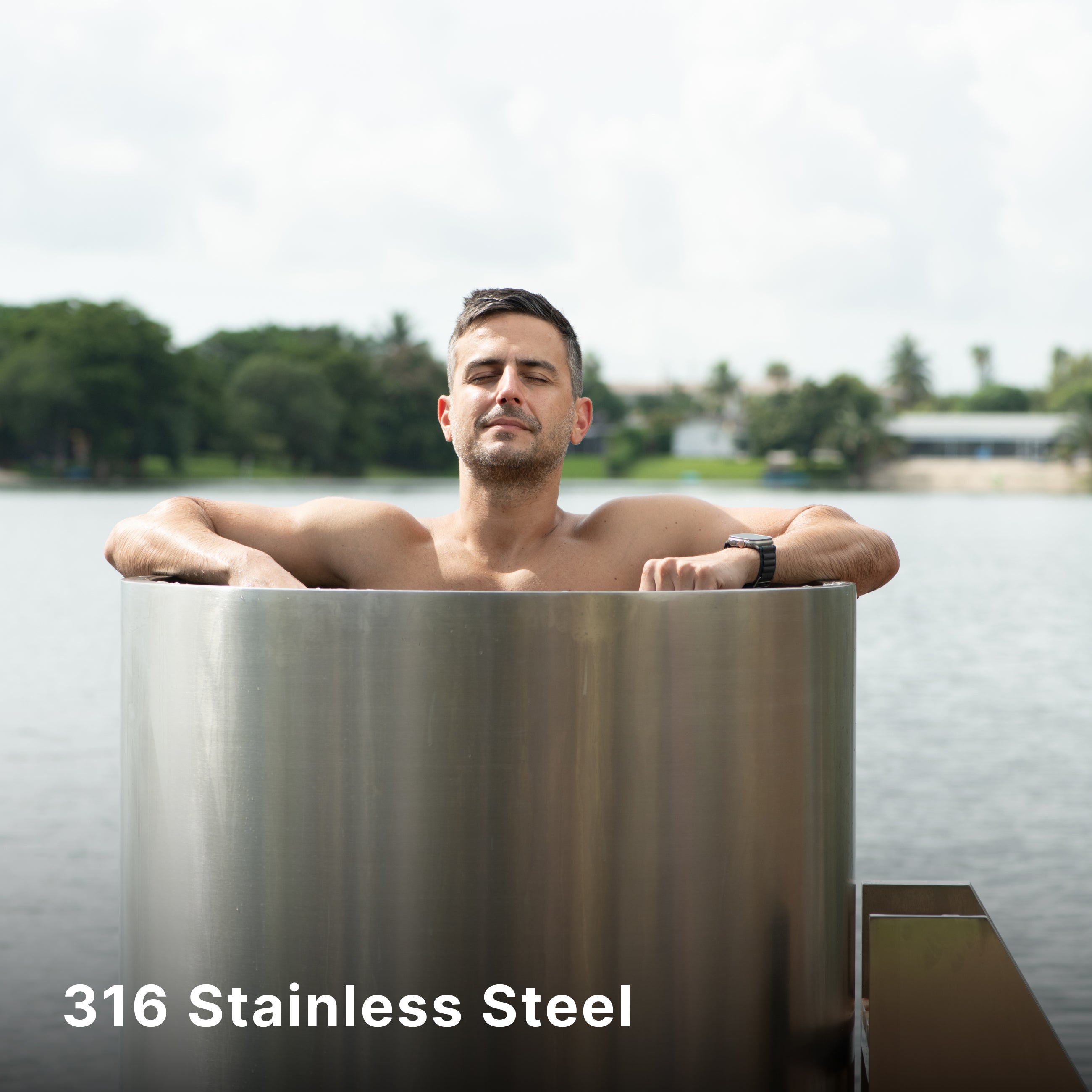 A man relaxes in a stainless steel ice bath outdoors, with his eyes closed and arms resting on the tub’s edge. A lake and trees are visible in the background. Text reads: 316 Stainless Steel.