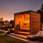The Mira Natural Sauna, featuring a modern wooden design with glass doors, is warmly illuminated at dusk and nestled among landscaped gardens with a lounge chair nearby. Seamlessly blending into its surroundings, this sauna creates a tranquil retreat that exemplifies harmonious indoor-outdoor living.