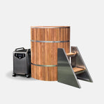 The Star Treatment 2.0 Cold Plunge is a cylindrical wooden tub with metal bands, an integrated seat, black wheeled control unit, and metal stairs—set on a plain white background, making it ideal for compact spaces.