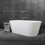 The Brainpod 2.0, a modern white freestanding bathtub with ergonomic design (69 or 73 long, 23.5 high, 31.5 wide), sits on a stone floor, with a small metallic machine placed next to it on the left.