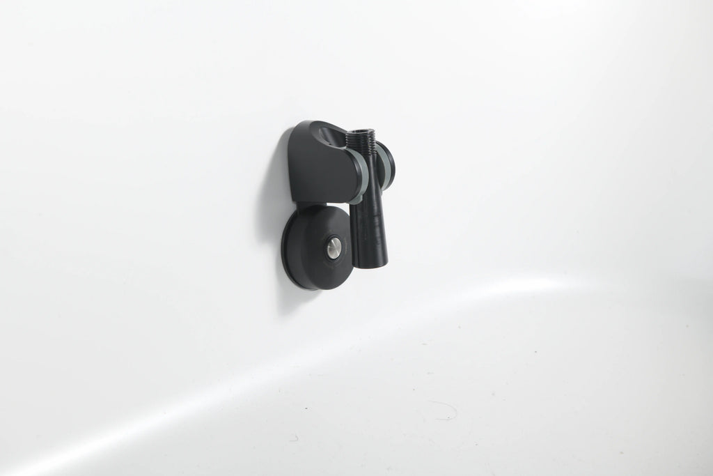 The Brainpod 2.0 Cold Plunge is a black, artist-designed wall-mounted holder with an ergonomic, cylindrical opening to securely hold your showerhead on a white bathroom wall.