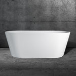 The Brainpod 2.0, a modern white freestanding bathtub with smooth curves and ergonomic design, is placed on a gray marble floor against a textured dark gray concrete wall.