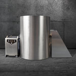 The Cyber Barrel, a tall cylindrical machine with a vertical design made from marine-grade stainless steel, stands against a concrete wall. It has an attached rectangular chute and a separate wheeled control unit on the left.
