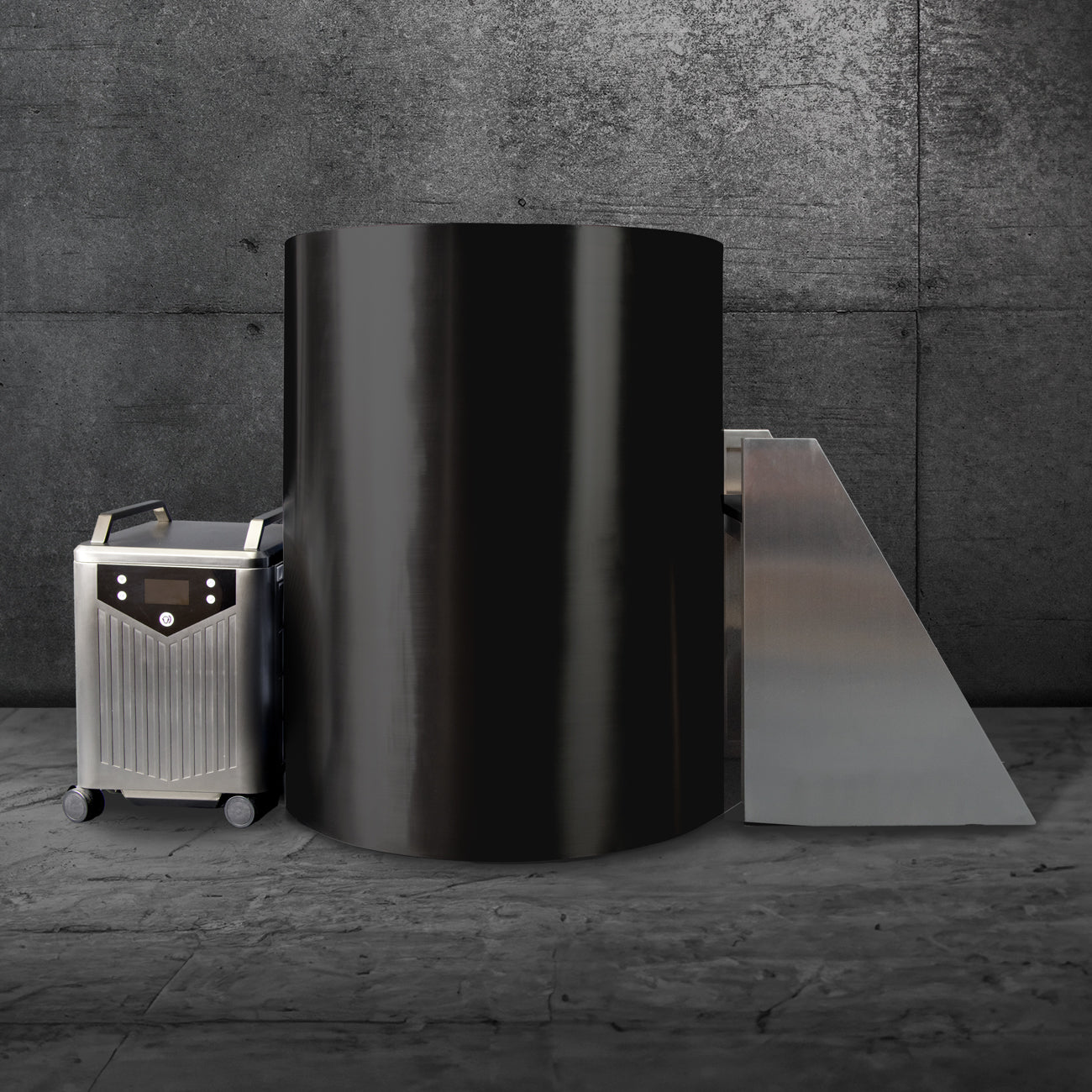 The Cyber Barrel, a sleek vertical cryotherapy chamber with a marine-grade stainless steel exterior, stands on a stone floor by a gray concrete wall beside its control unit and angled platform.