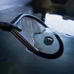 A close-up of the Skimmer Net’s stainless steel mesh, partially submerged and reflecting light on rippled water—perfect for efficient debris removal during a cold plunge skimmer session.