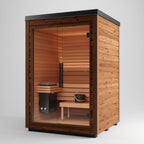 The Aura Auroom Sauna is a small, modern outdoor cabin with horizontal wood paneling, a sleek black flat roof, glass front door, interior bench, sauna heater, and a bucket with ladle for heat therapy.