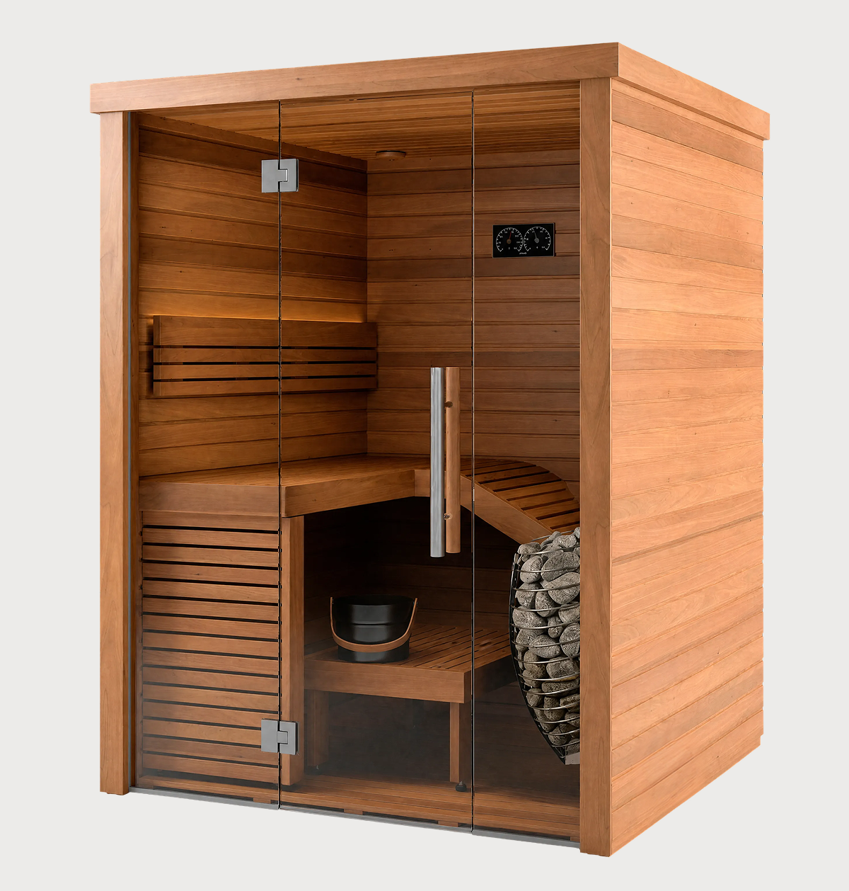 The Baia Glass Sauna is a modern sauna with sleek wooden panels and glass doors, featuring an interior bench, a bucket with ladle, a stone heater, and a temperature gauge on the wall. This indoor sauna offers a warm, inviting appearance perfect for relaxation.