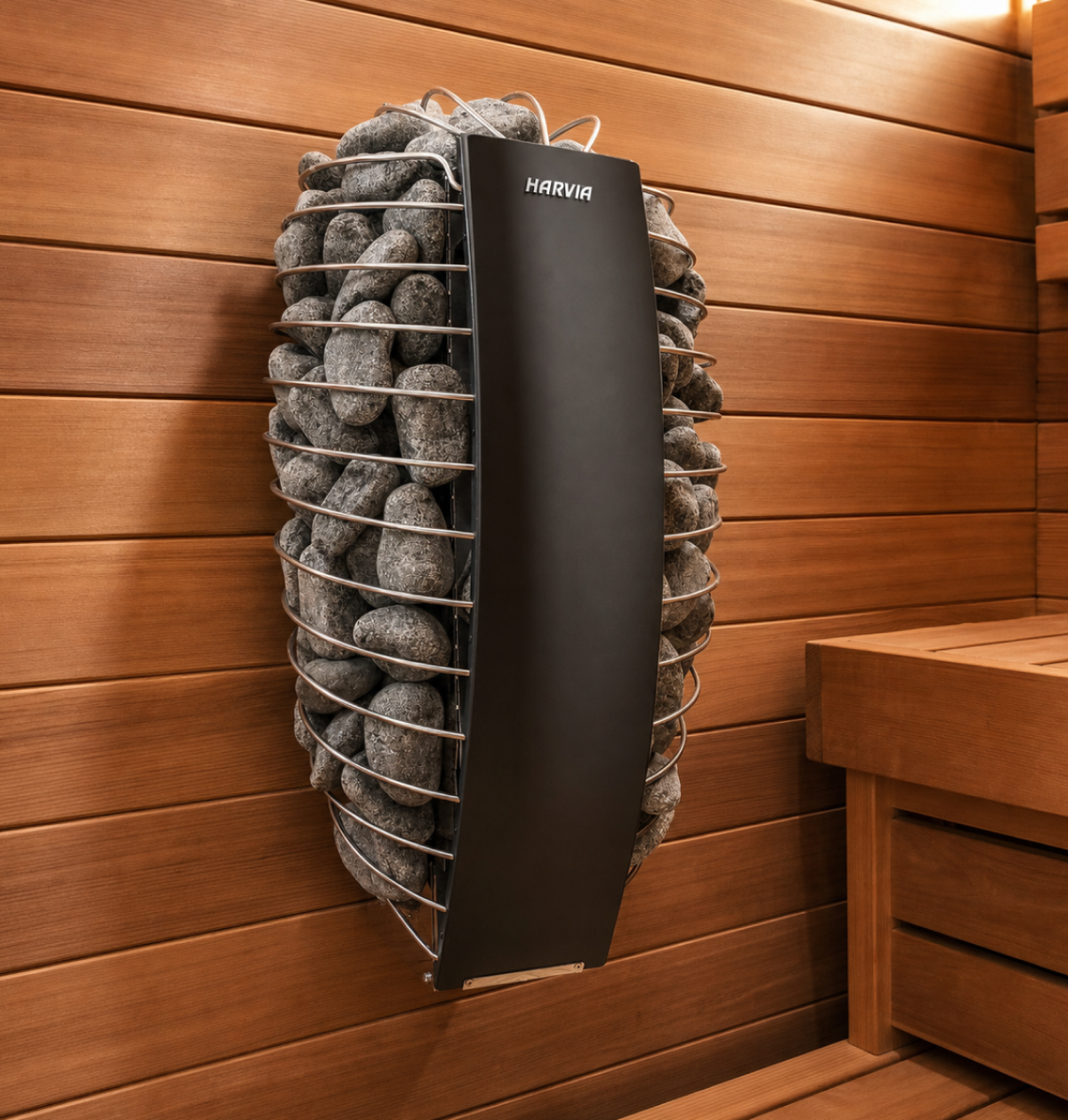 The Baia Glass Sauna features a modern sauna heater filled with gray stones, mounted on a wooden wall inside an indoor sauna room with light brown wood panels and a nearby wooden bench.