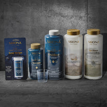 The 6 Month Sanitation Kit, featuring six Sirona Spa Care products—including sanitizer and test strips—is arranged on a gray stone surface with a matching background. A small plastic cup sits in front, ideal for spa or cold plunge use.
