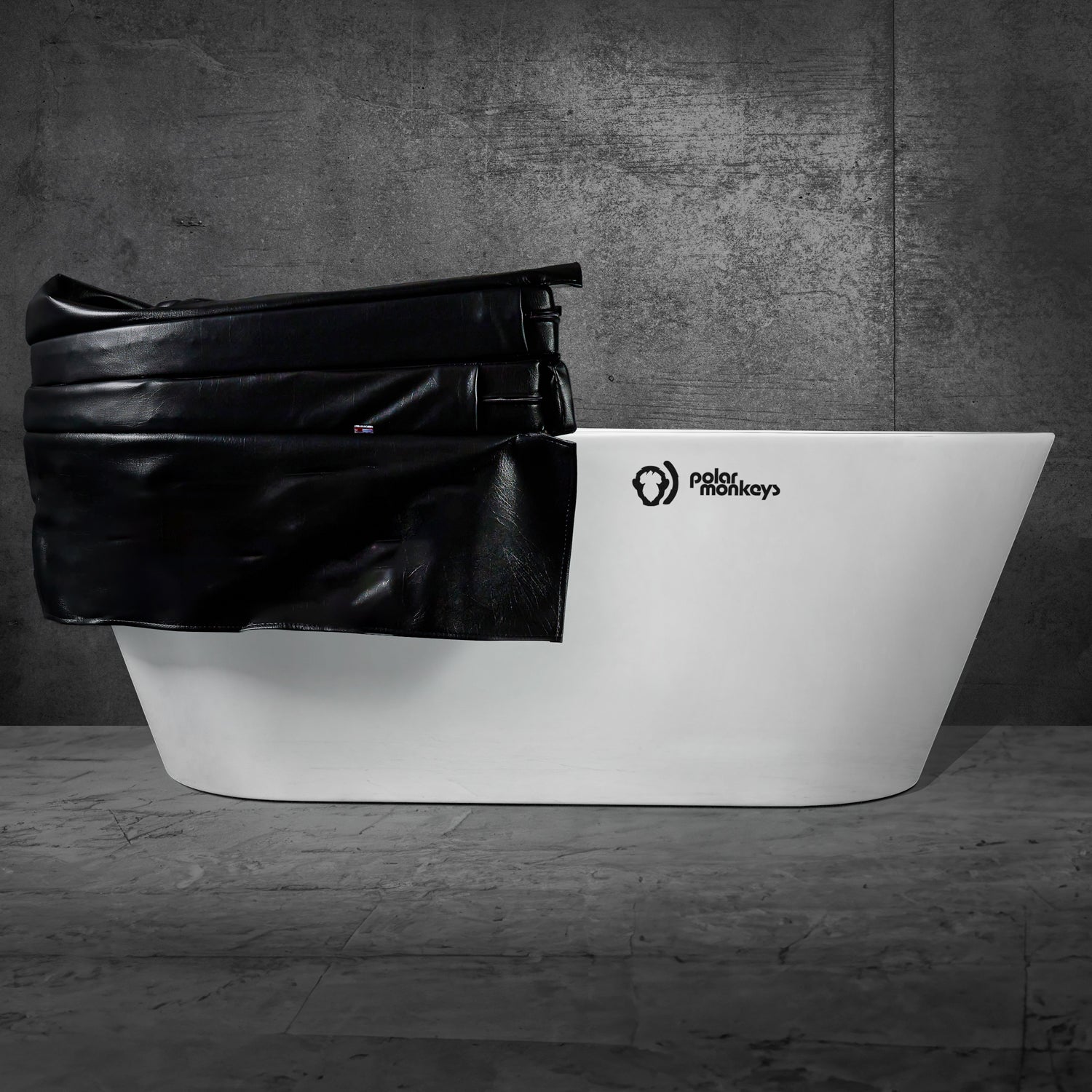 A modern white bathtub with the Polar Monkeys logo is partially covered by the Insulated Cold Plunge Cover, made from marine-grade synthetic leather and insulation foam, set against a dark textured wall and marble floor.