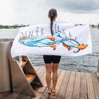 A person with wet hair stands on a dock by the water, facing away, with a quick-drying PolarMonkeys Polar Monkeys Towel featuring a colorful swimming figure and splashes draped across their back.