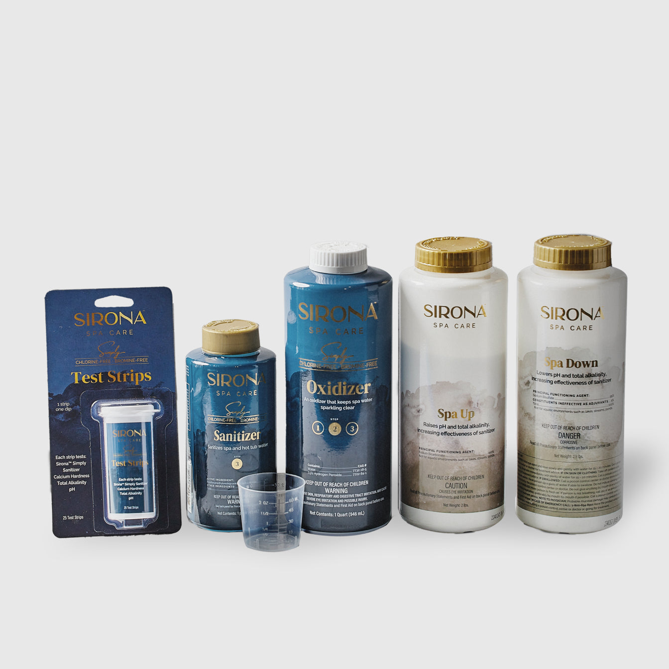 The Sirona Spa Care 6 Month Sanitation Kit, featuring test strips, sanitizer, oxidizer, Spa Up, and Spa Down bottles, is displayed side by side with a small measuring cup in front on a plain background.