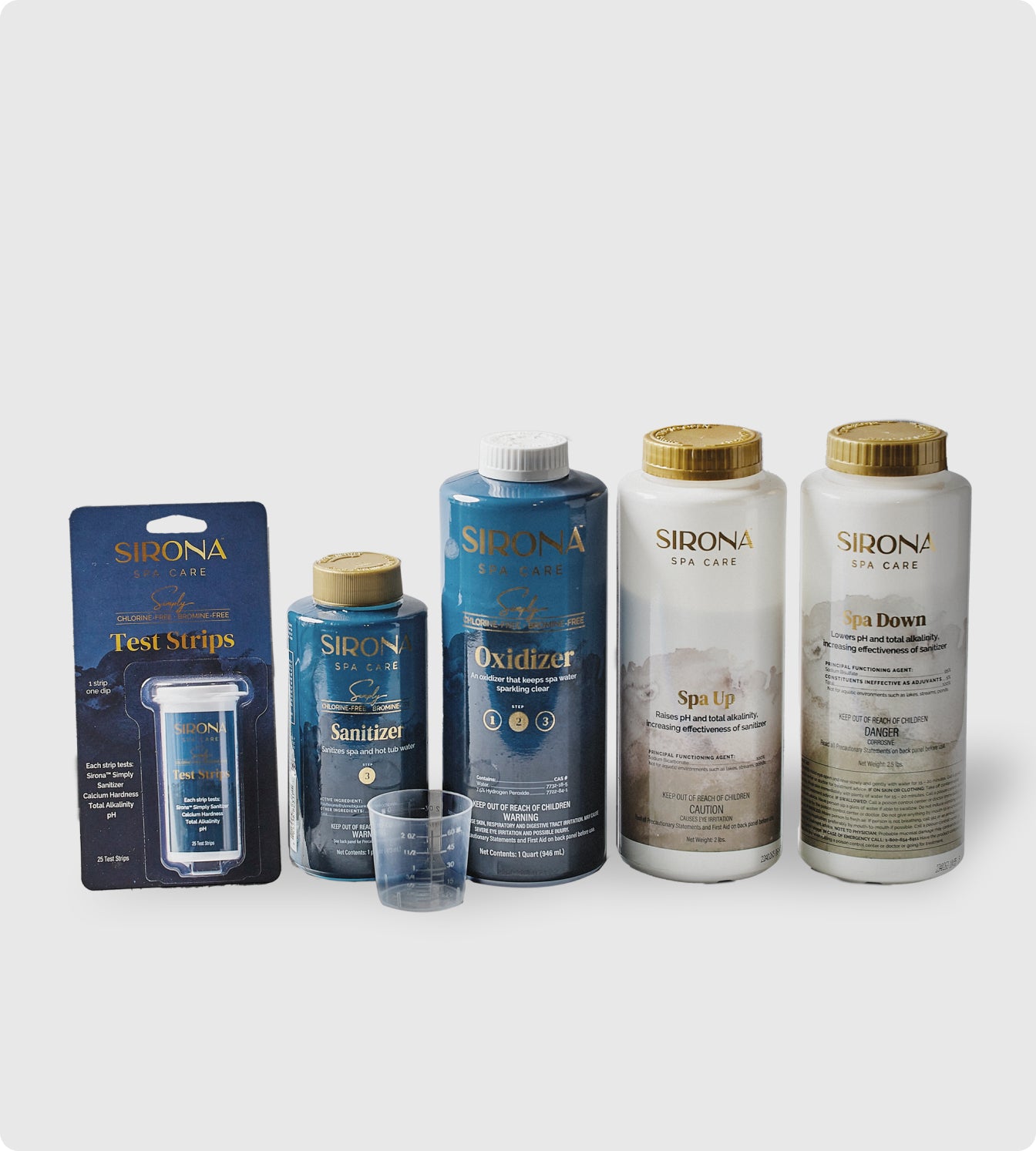 The Sirona Spa Care 6 Month Sanitation Kit, featuring test strips, sanitizer, oxidizer, Spa Up, and Spa Down bottles, is displayed side by side with a small measuring cup in front on a plain background.